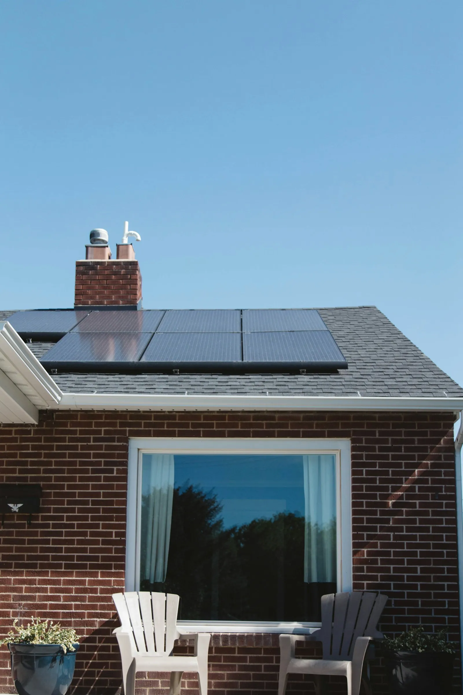 Une maison de brique avec des panneaux solaires sur le toit, sous un ciel bleu dégagé