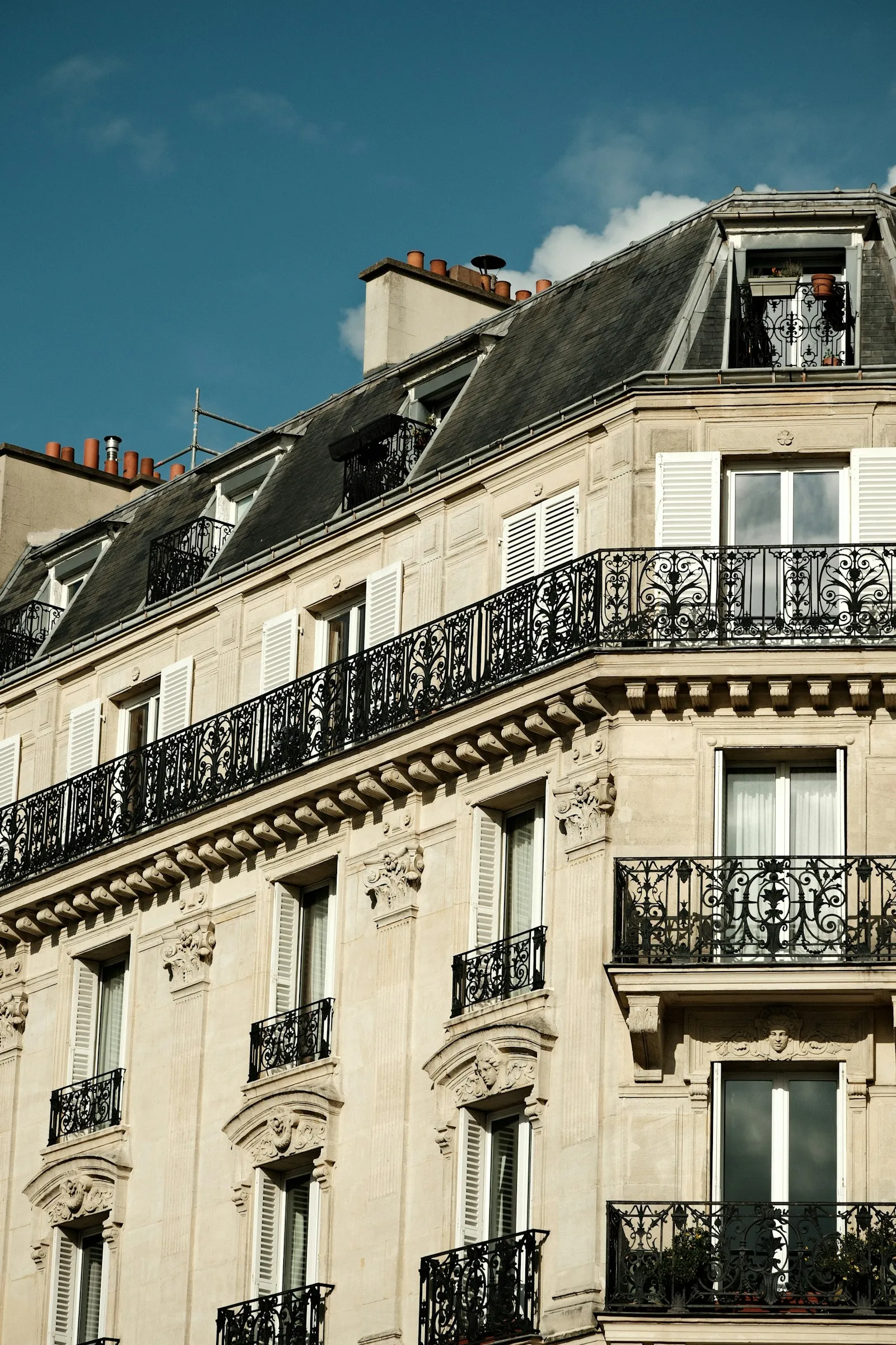 Un bel immeuble ancien en pierre claire avec toit en zinc, sous un ciel bleu