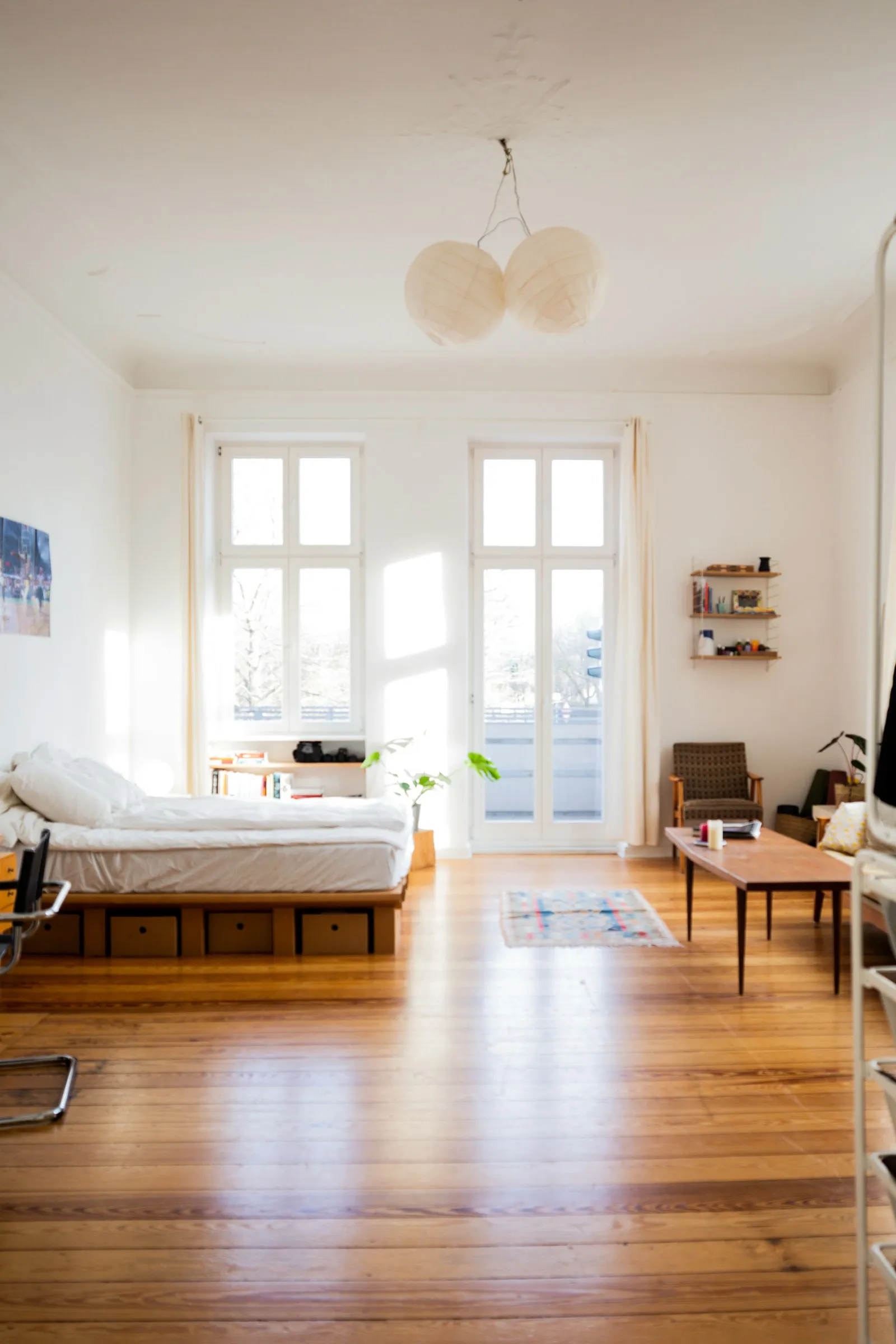 Un studio très lumineux avec parquet, grandes fenêtres, un lit et une table basse