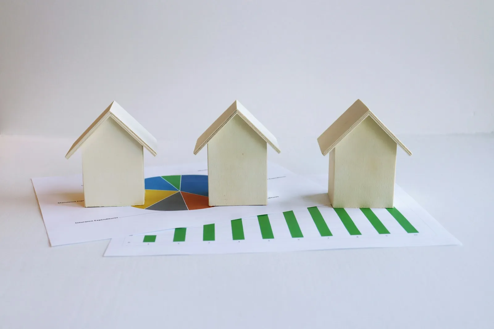 Trois petites maisons en bois clair posées sur des feuilles de graphiques