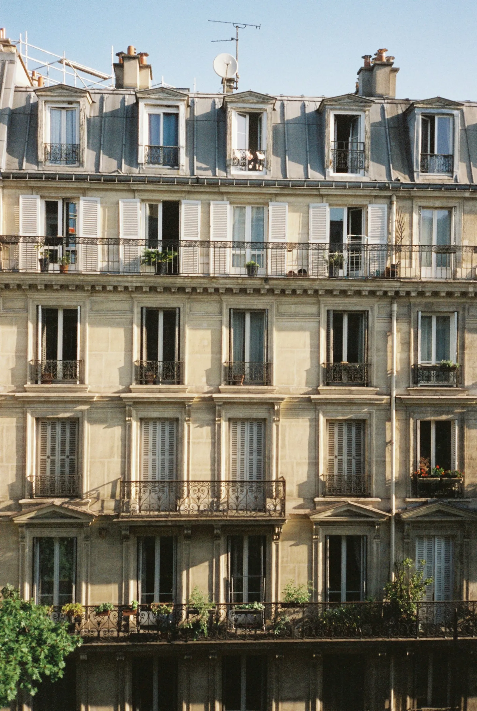 La façade en pierre d'un immeuble ancien bien entretenu, avec balcons et persiennes