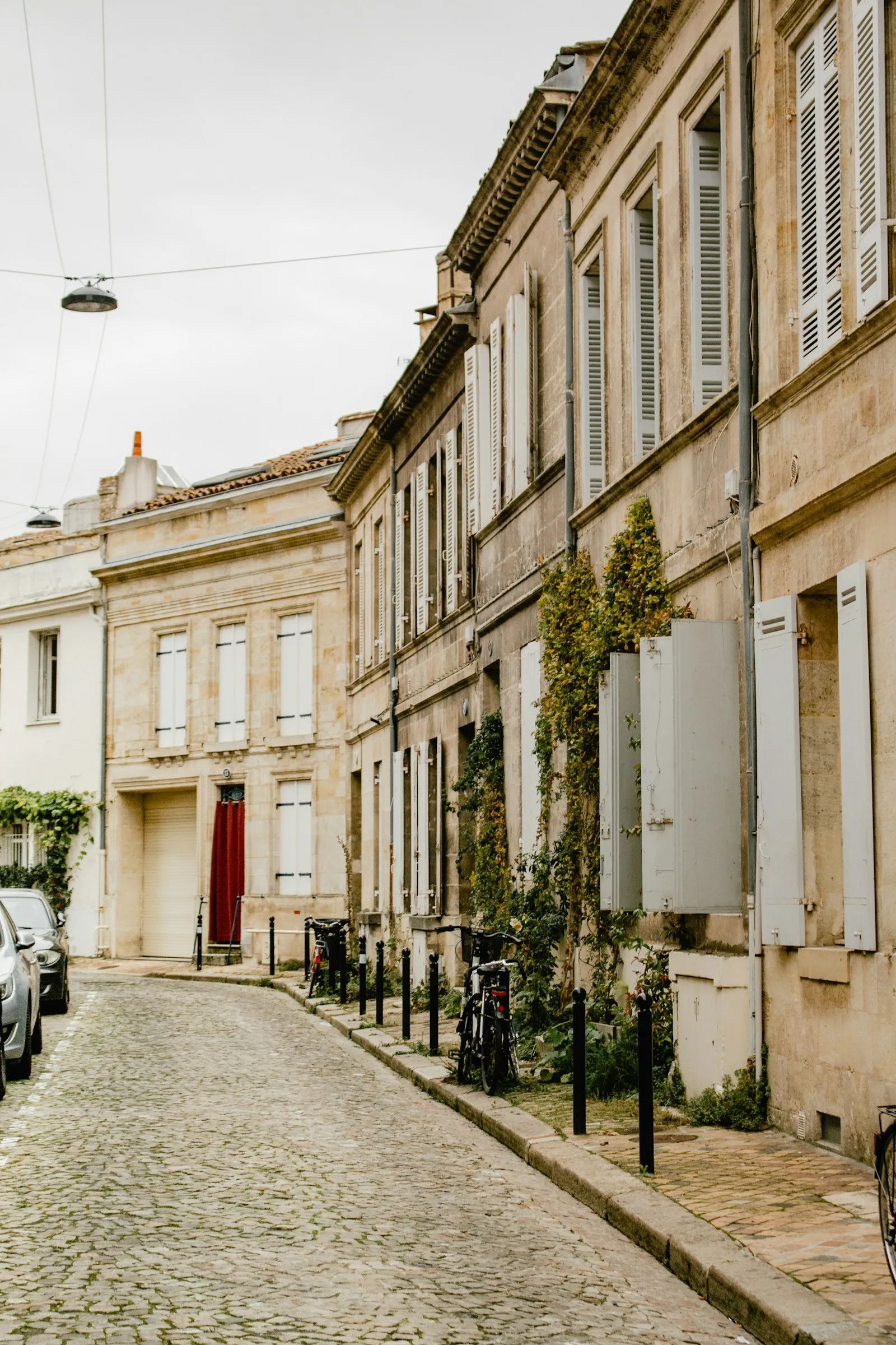 Une rue pavée calme de Bordeaux bordée de façades en pierre blonde et de volets
