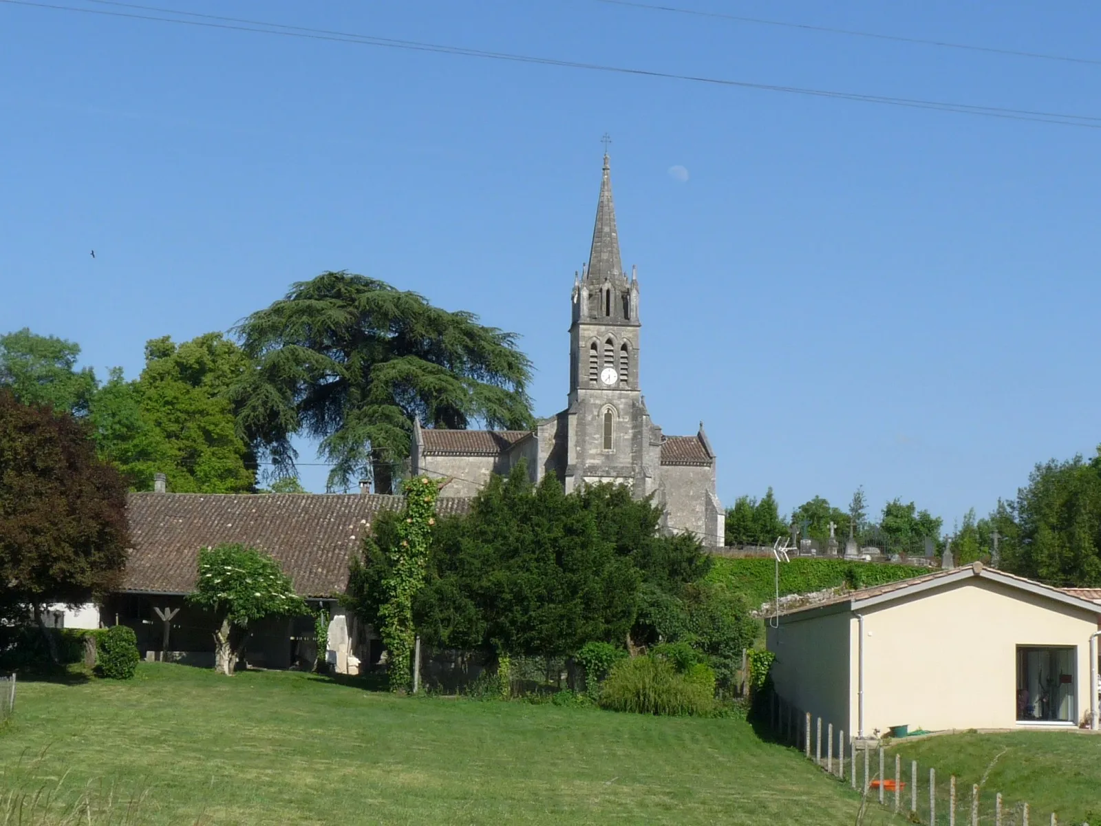 Le clocher de l’église Saint-Genès de Bonzac au-dessus des maisons et des arbres du village