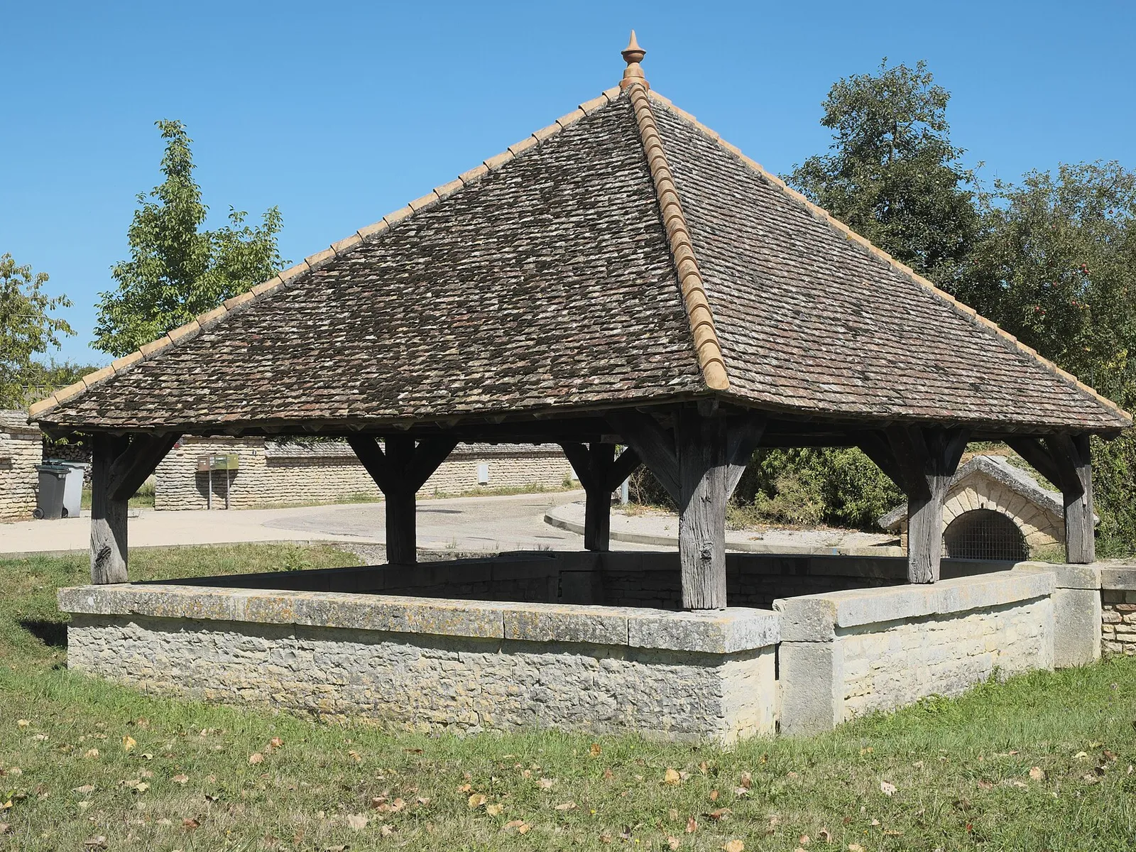 Le lavoir couvert de Crissey, toit de tuiles sur charpente en bois, sous un ciel bleu