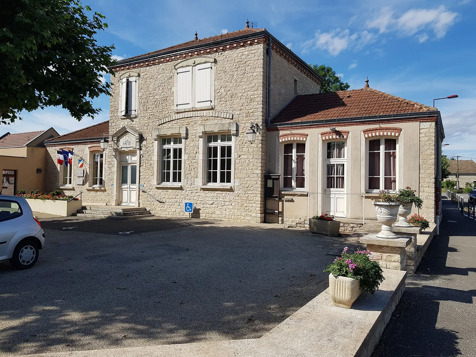 La mairie de Lans, bâtiment en pierre claire sur sa place, sous un ciel bleu