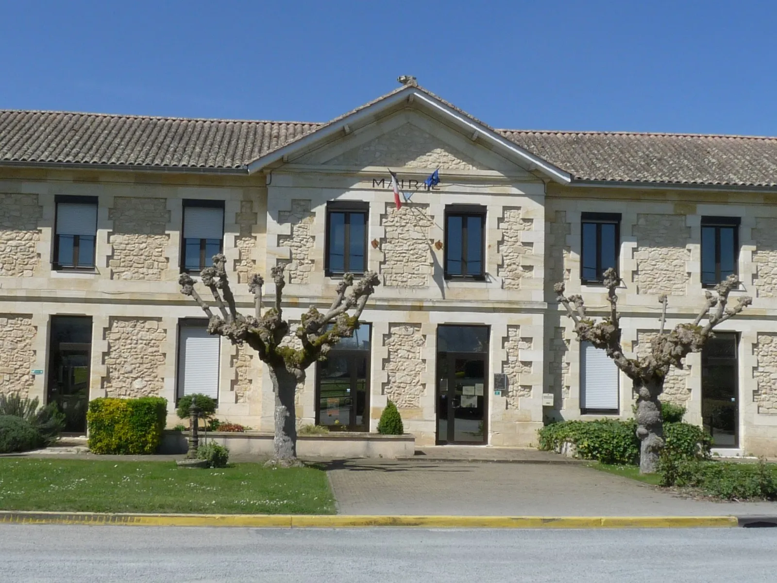 La mairie des Peintures, bâtiment en pierre précédé de deux arbres taillés
